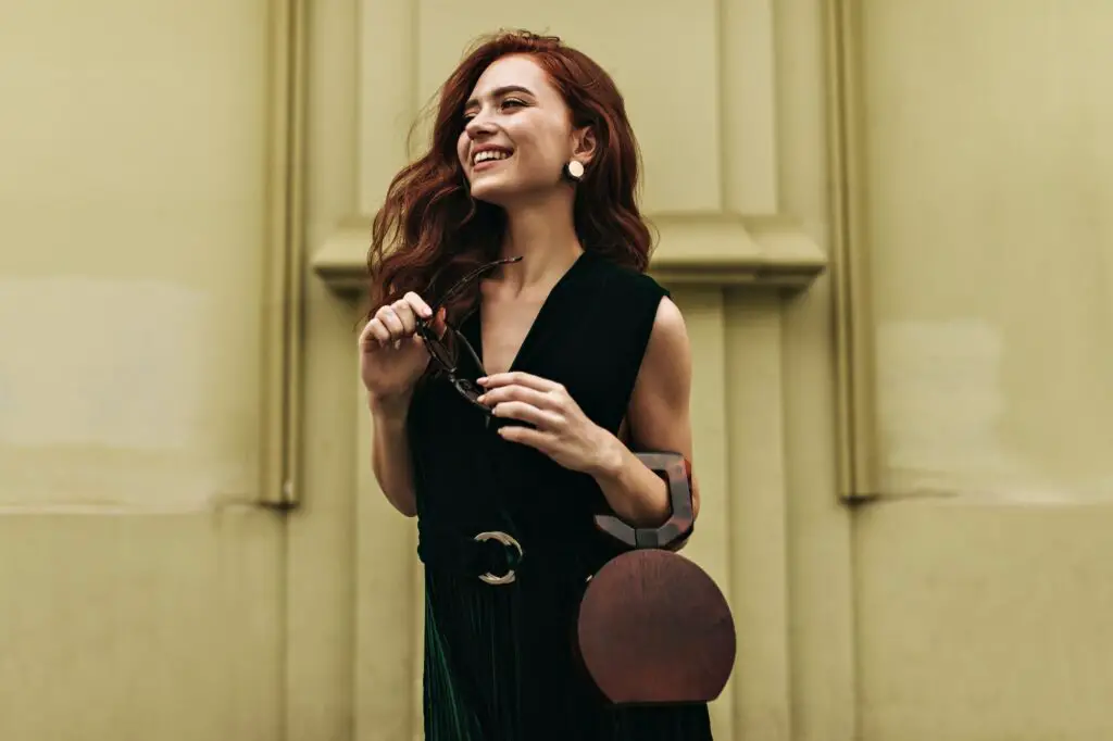 Ginger woman holds handbag and smiles