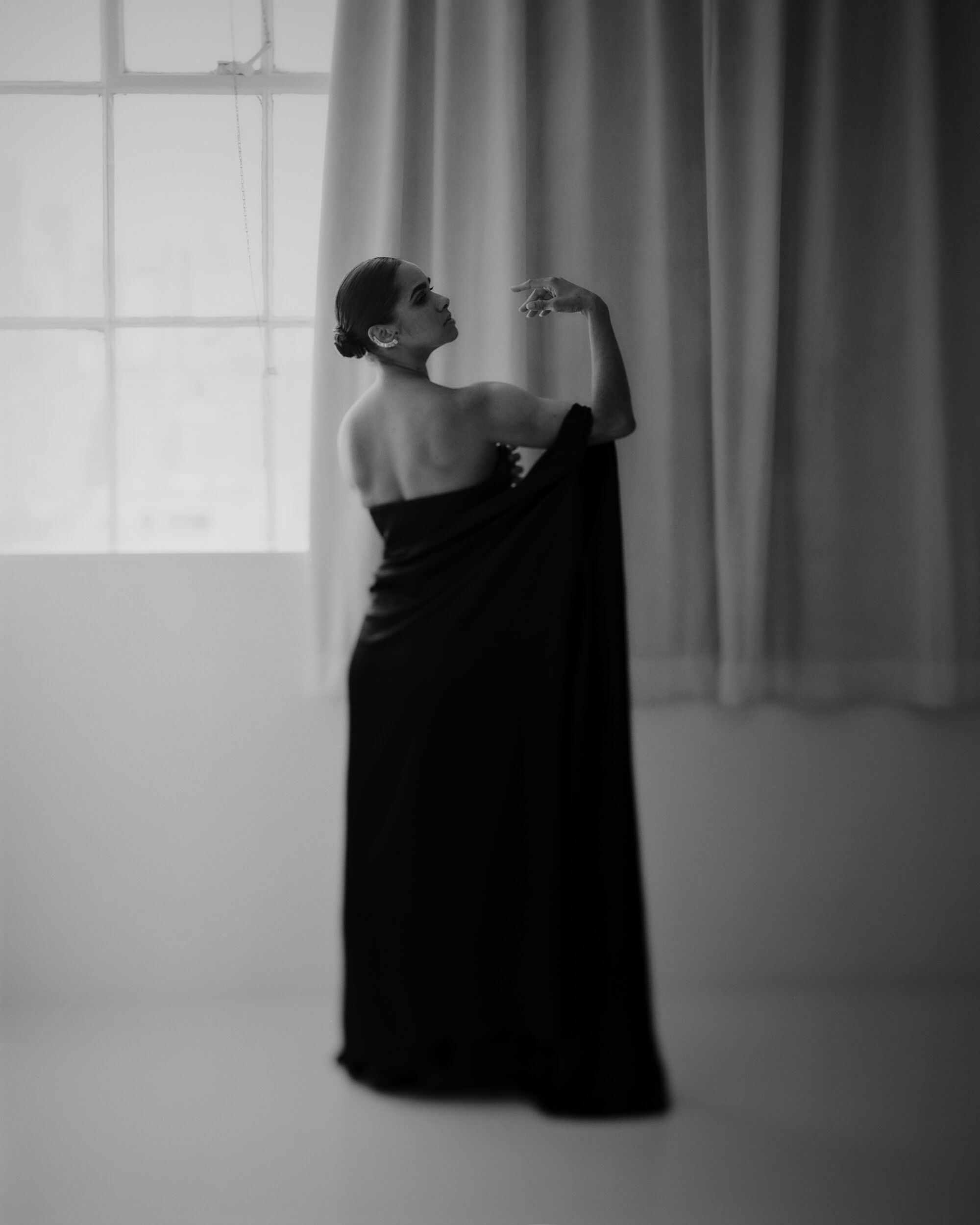 Black and white photo of Copeland in a long black dress, lifting her arm in a dancerly manner.