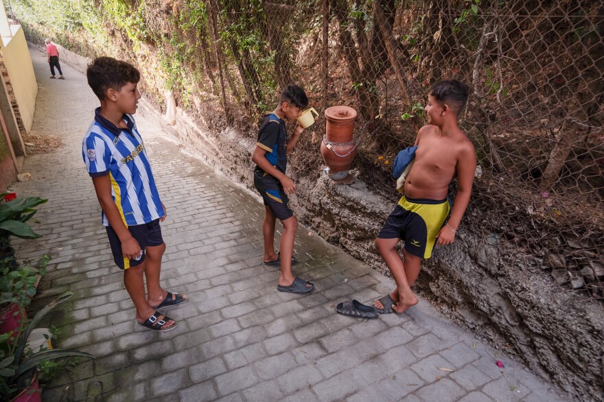 Thirsty boys drinking the golla's cooler water on a street in Tangier. Some community members place gollas in public spaces so that everyone has access to water.