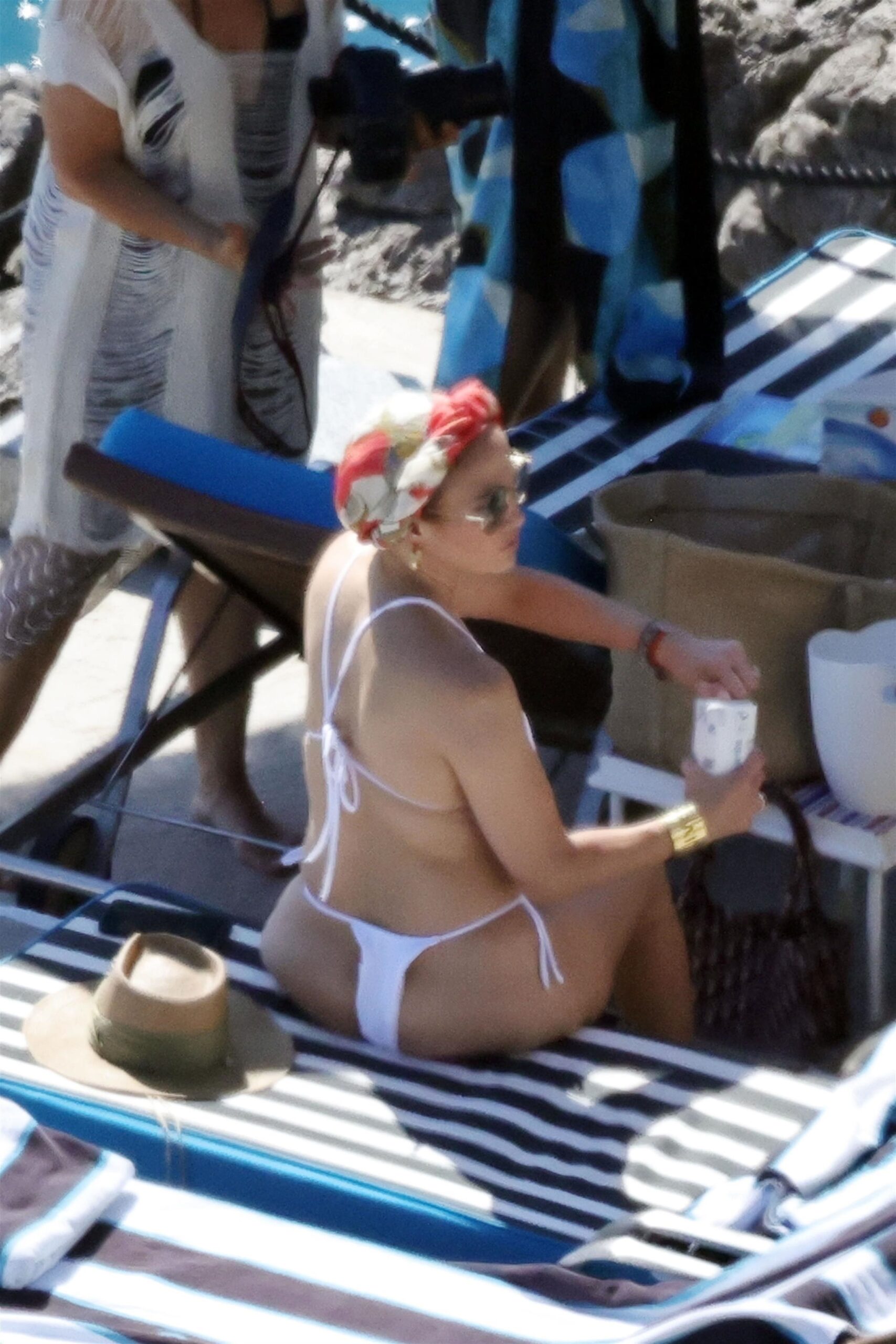 Jennifer sat on the sun bed while wearing a bandana