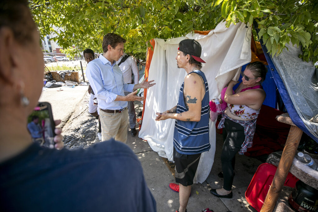Mayor Mike Johnston (left) speaks with David Sjoberg, a resident of an encampment at 22nd and Stout Streets that's set to be swept. Aug. 3, 2023.