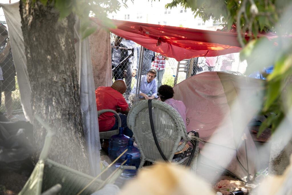 Mayor Mike Johnston speaks with residents of an encampment at 22nd and Stout Streets, one day before it's swept. Aug. 3, 2023.
