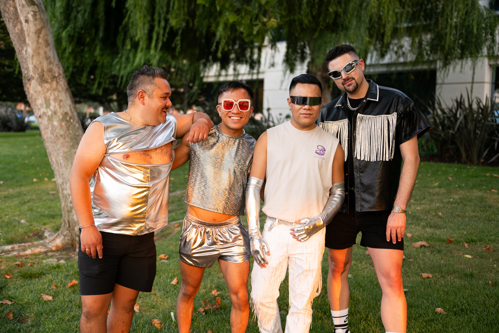 Four people stand together wearing silver and black clothing.