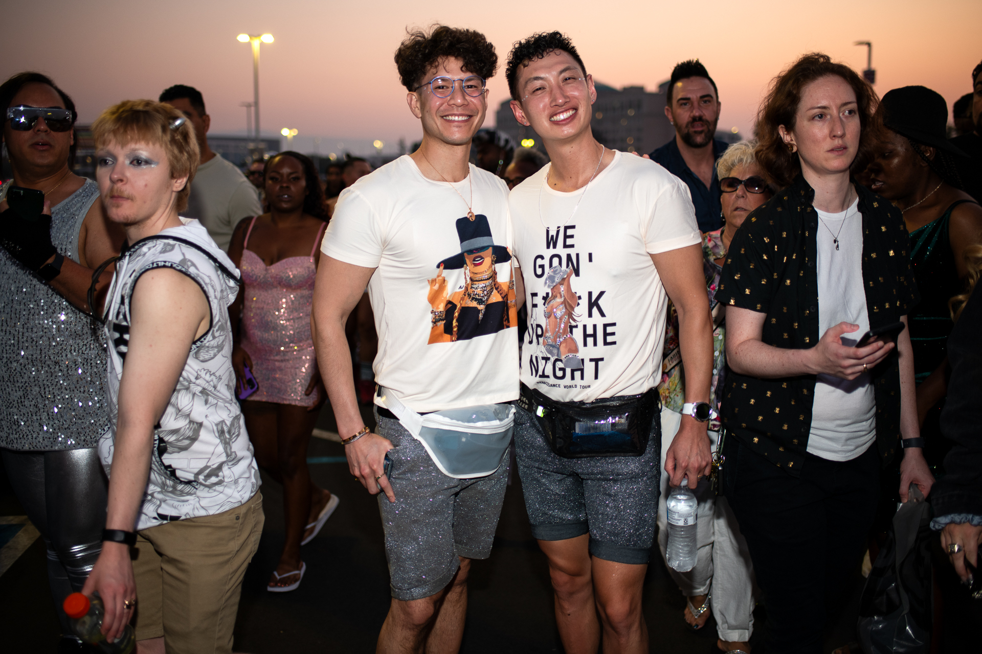 Two people smile facing the camera in white t-shirts and silver shorts.