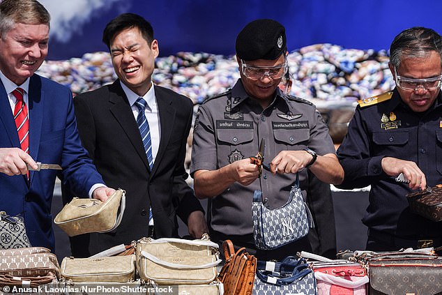Thai officer cuts in pieces confiscated counterfeit fashion during a destruction ceremony of intellectual property rights infringing goods in Bangkok, Thailand, 31 August 2023