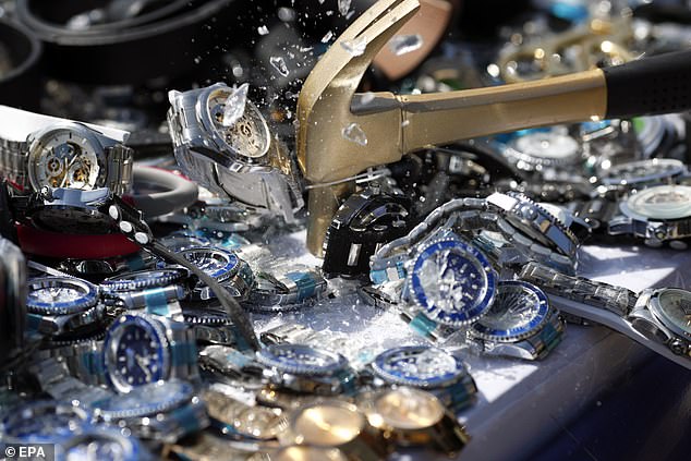 A participant smashes counterfeit watches with a hammer during a destruction ceremony of intellectual property rights infringing goods in Bangkok, Thailand, on August 31, 2023