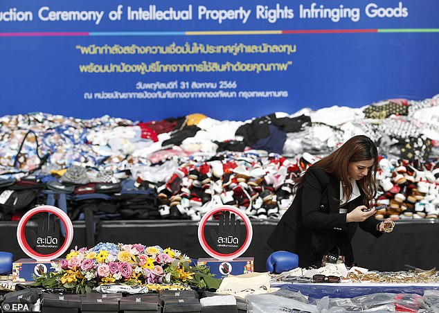 An injured person from a business firm inspects counterfeit goods during a destruction ceremony of intellectual property rights infringing goods in Bangkok, Thailand, 31 August 2023