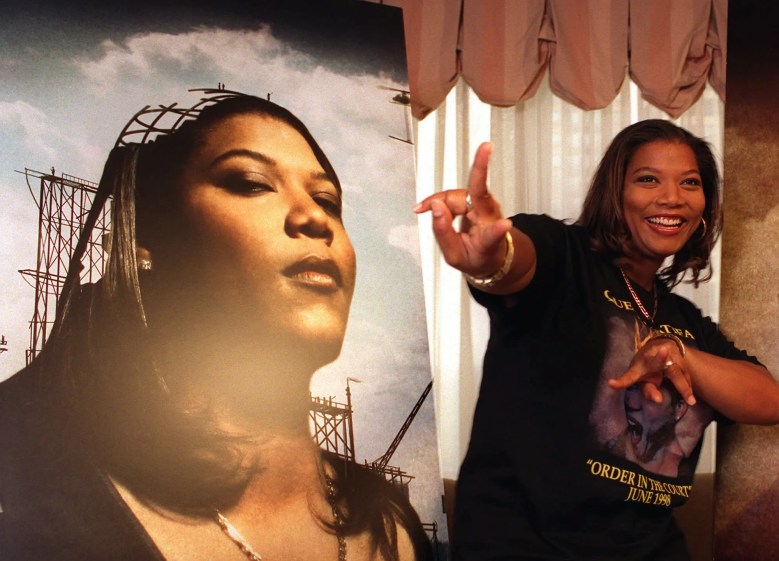 Queen Latifah poses next to a poster of herself