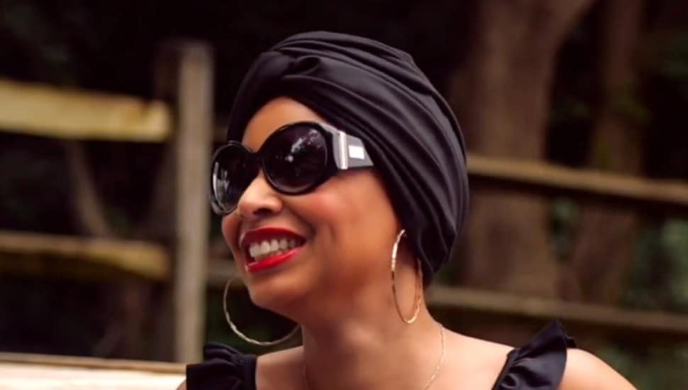woman smiling in sunglasses hoop earrings wearing hair wrap or turban