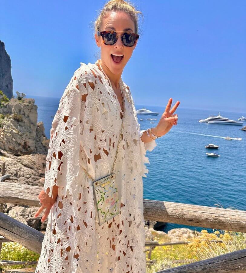 Ellie poses in Capri with white lace coverup and a cell phone bag