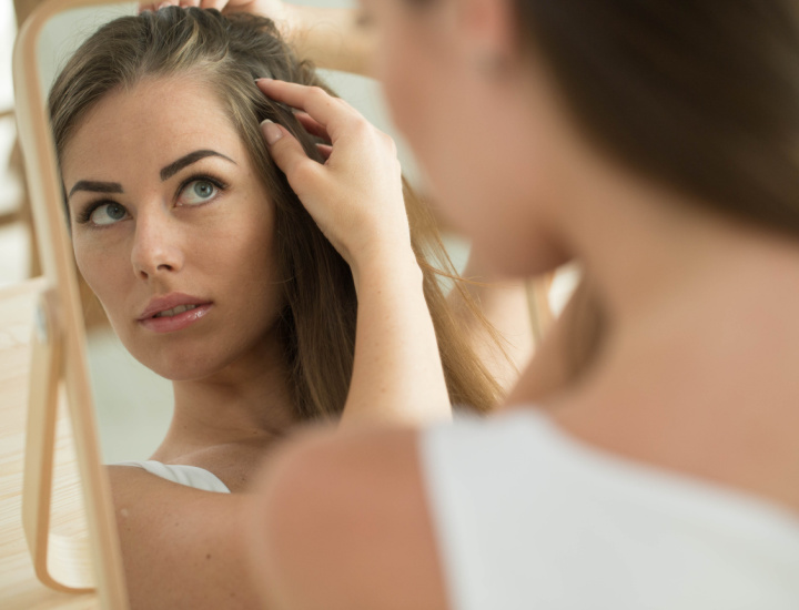 Woman examining hair in the mirror