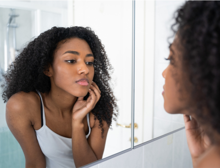 Woman examining face in mirror