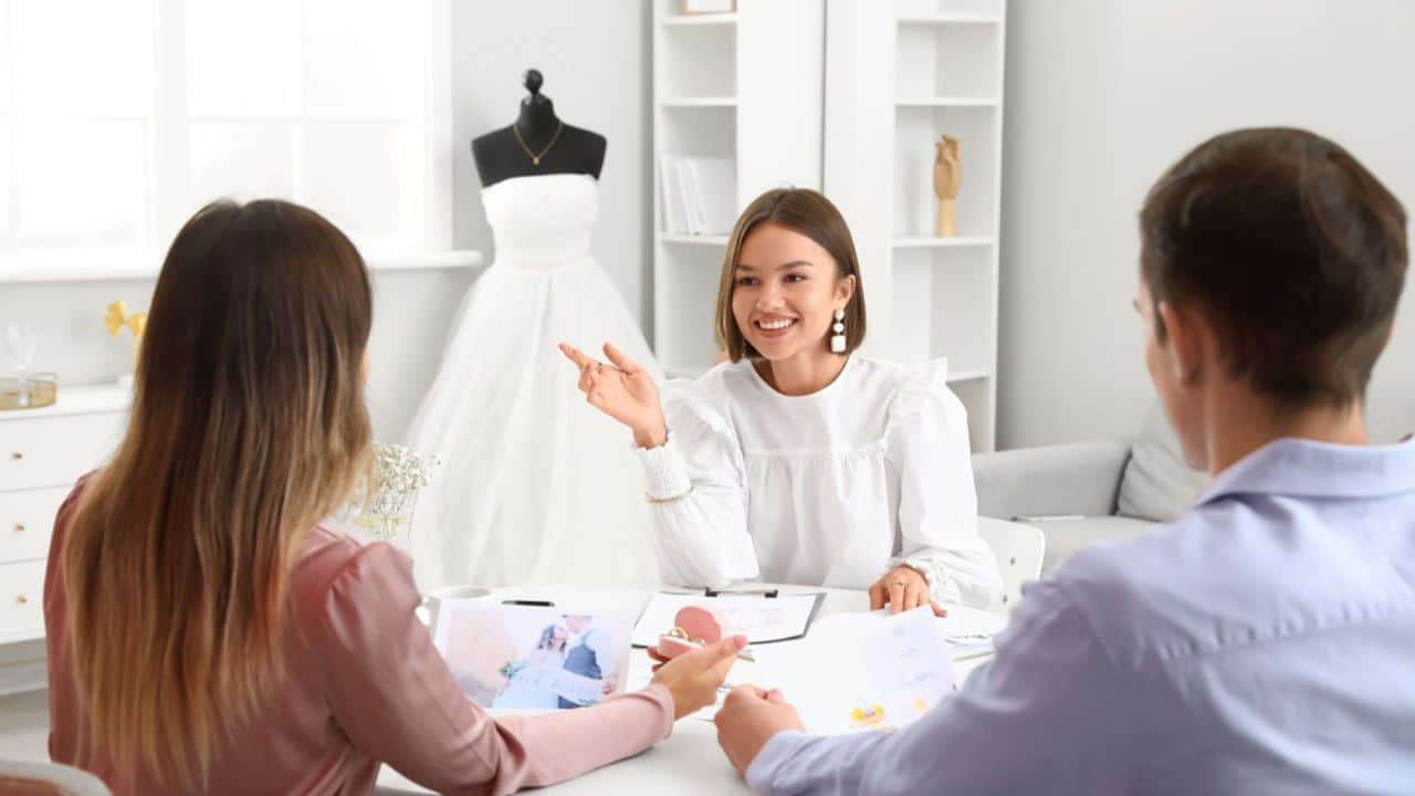 Female wedding planner discussing ceremony with clients in office