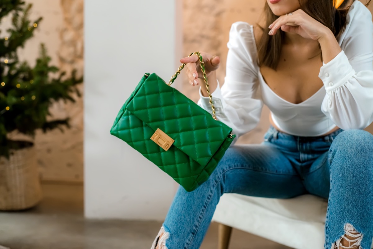 Trendy outfit woman with black bag. Girl with bag over his shoulder outdoors. Shoulder Bags for Women. Fashion look woman outfit. Stylish women's beige handbag. Close-up.