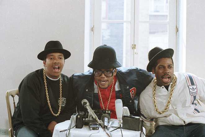 FILE - Rap group RUN D.M.C., in London for two concerts, talk during a news conference. The group, left to right, is Joseph Simmons, Darryl McDaniels,  and Jason Mizell. The signs of hip-hop’s influence are everywhere — but it didn&apos;t start out that way. Even though the company had seen an unusual spike in sales of its Superstar shoes in the Northeast in 1986, it wasn&apos;t ready to attribute that to Run-D.M.C. and their hit “My Adidas.” When company execs saw the group ask fans to show off their Adidas and thousands removed their shoes and waved them in the air at a Madison Square Garden performance, they were sold. They signed the rap group to a $1 million deal that resulted in their own shoe line in 1988.  (AP Photo/Peter Kemp, file)