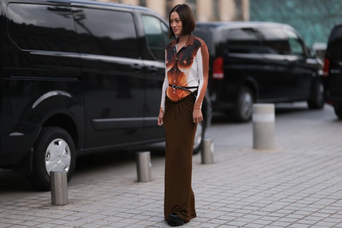 A woman in the street wears a long skirt with a top that features an image of breasts