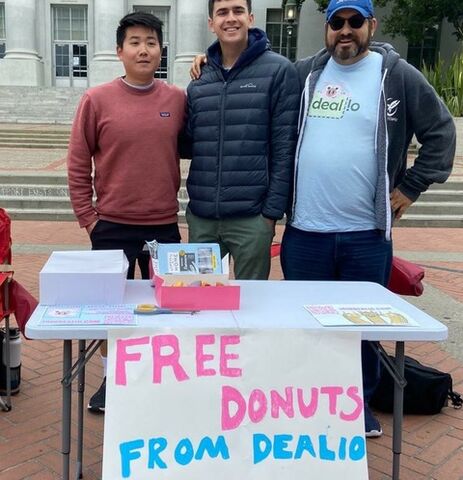 Three guys stand behind table with a handmade 