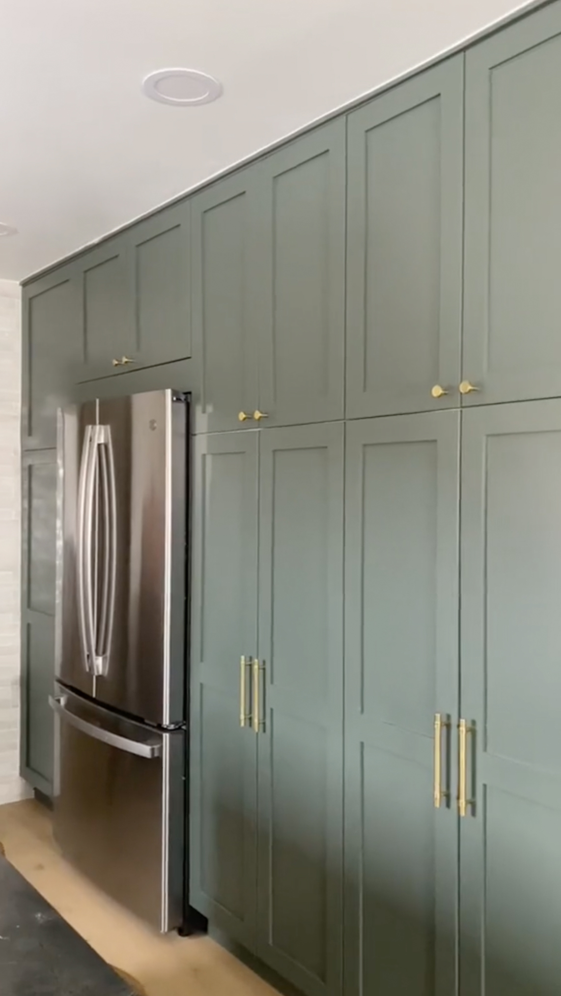 The kitchen now has modern green cupboards and white tiles on the walls