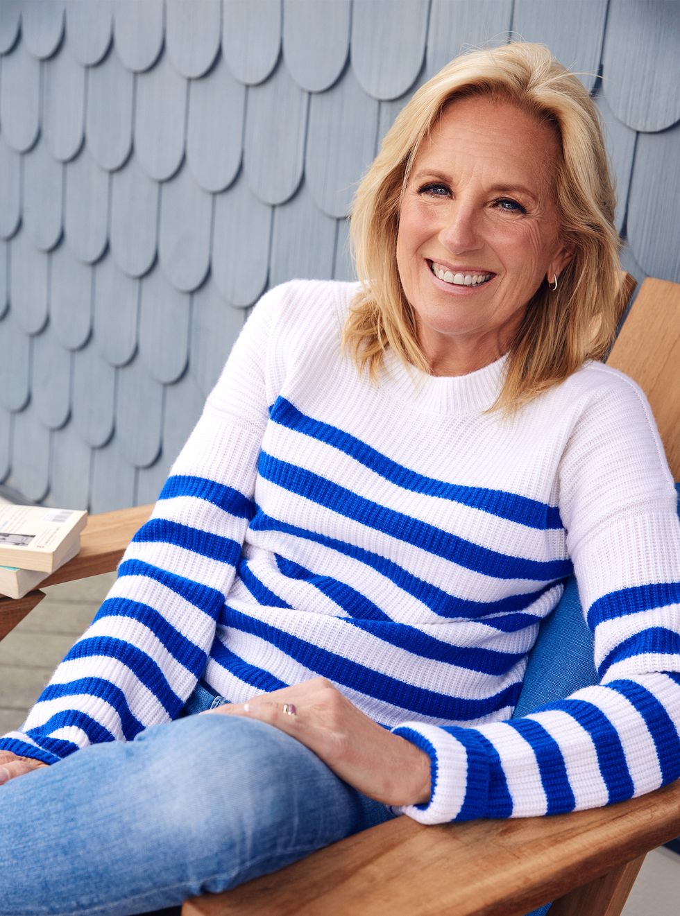 first lady jill biden sitting in a chair outside, smiling at the camera