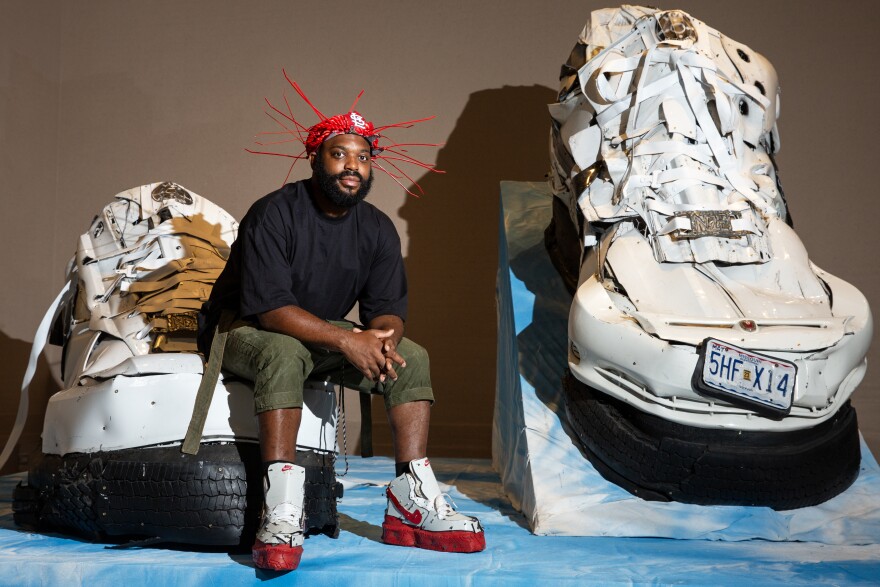 Artist Aaron Fowler alongside his sculpture “Live Culture Force 1’s, 2022” at the St. Louis Art Museum. Fowler’s work will be on display at the museum through the end of the year, as a part of its exhibit “The Culture: Hip Hop and Contemporary Art in the 21st Century.”