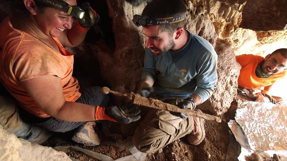 Removing the swords from the crevice where they were hidden. Photography Emil Aladjem Israel Antiquities Authority