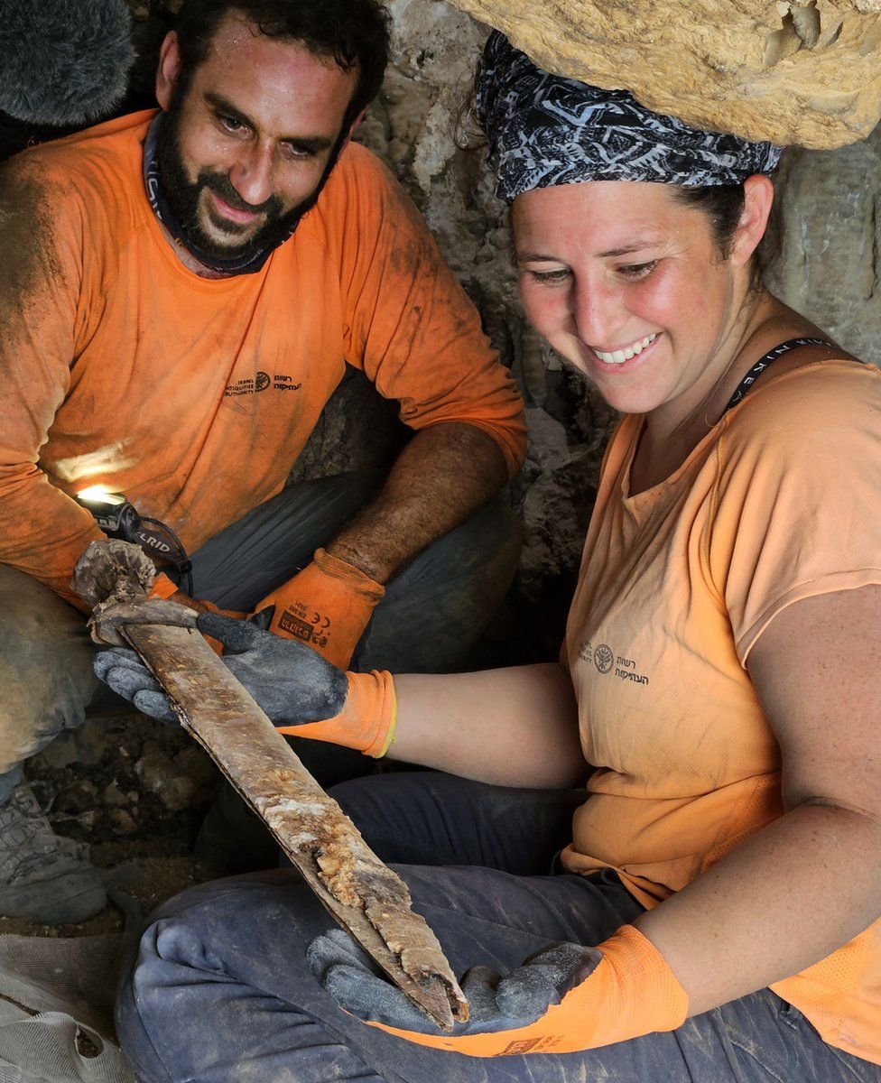 Archaeologists Oriya Amichay and Hagay Hamer with one of the swords found in the cave. Photography Amir Ganor Israel Antiquities Authority