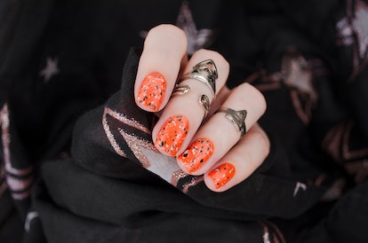 Orange matte nails with black and white splatter speckle print for fall nail design 