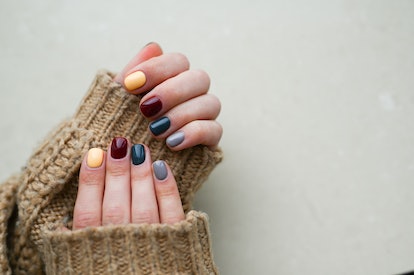 Women's hands with colorful autumn pattern on the nails