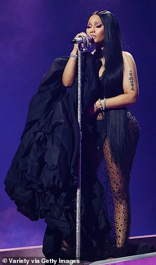 Layers: The hitmaker performed new music in a huge black coat with a slip dress underneath