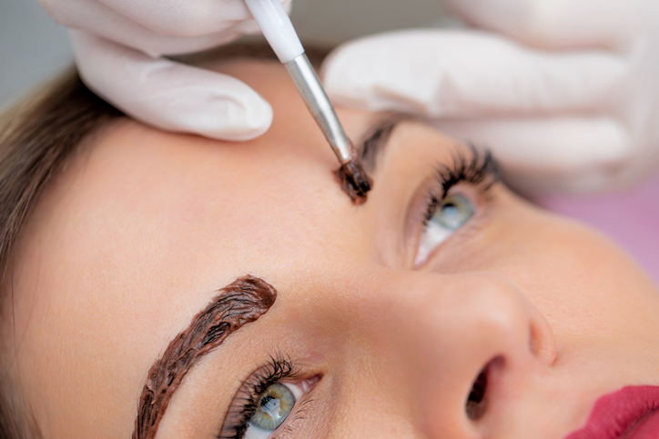 Woman getting sparse eyebrows tinted.