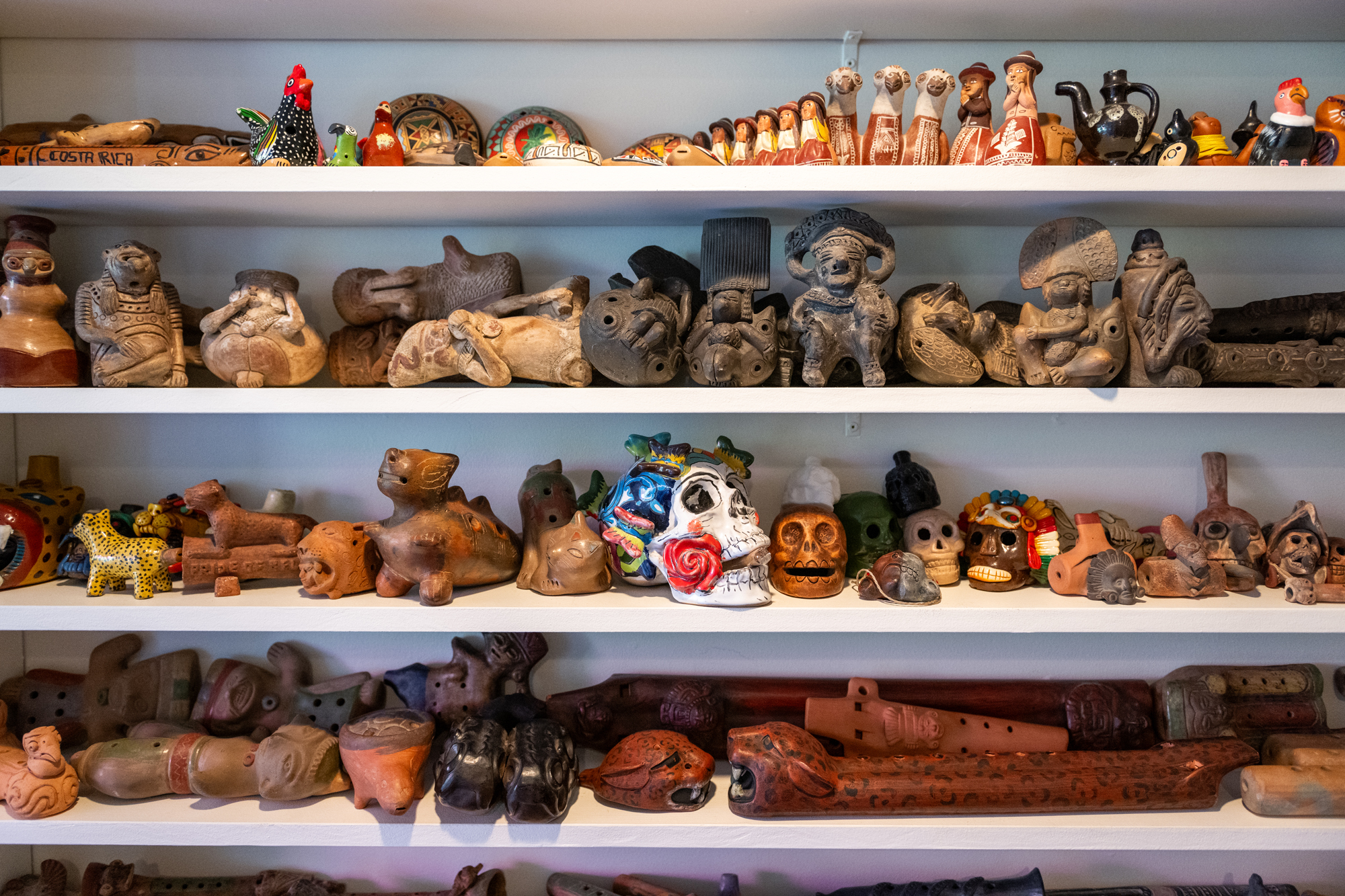 Four wide shelves with ceramic and wooden instruments densly arranged on them