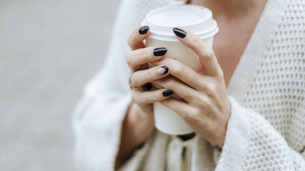 close up of woman's hands with take away drink