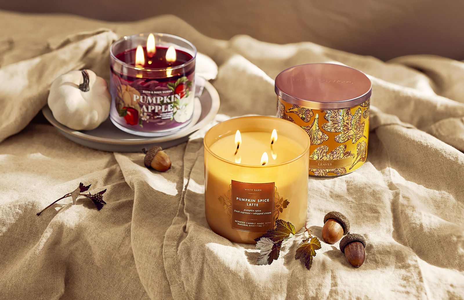 A display of three Bath & Body Works fall candles in various scents and colors