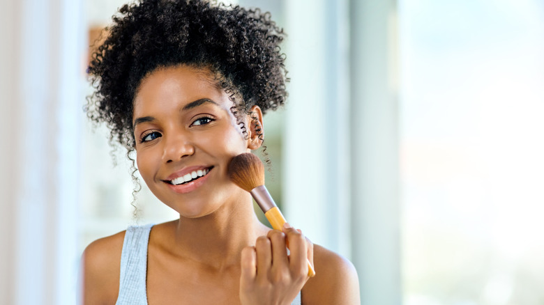 Woman applying makeup to face