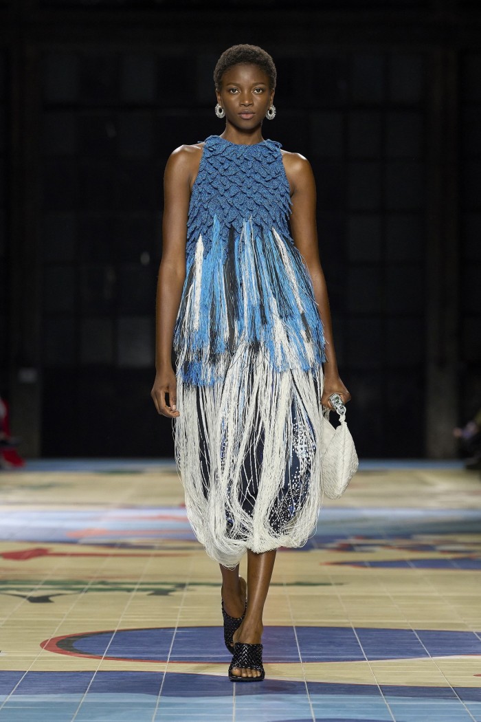 A catwalk model in a sleeveless knit dress of blue and whtie