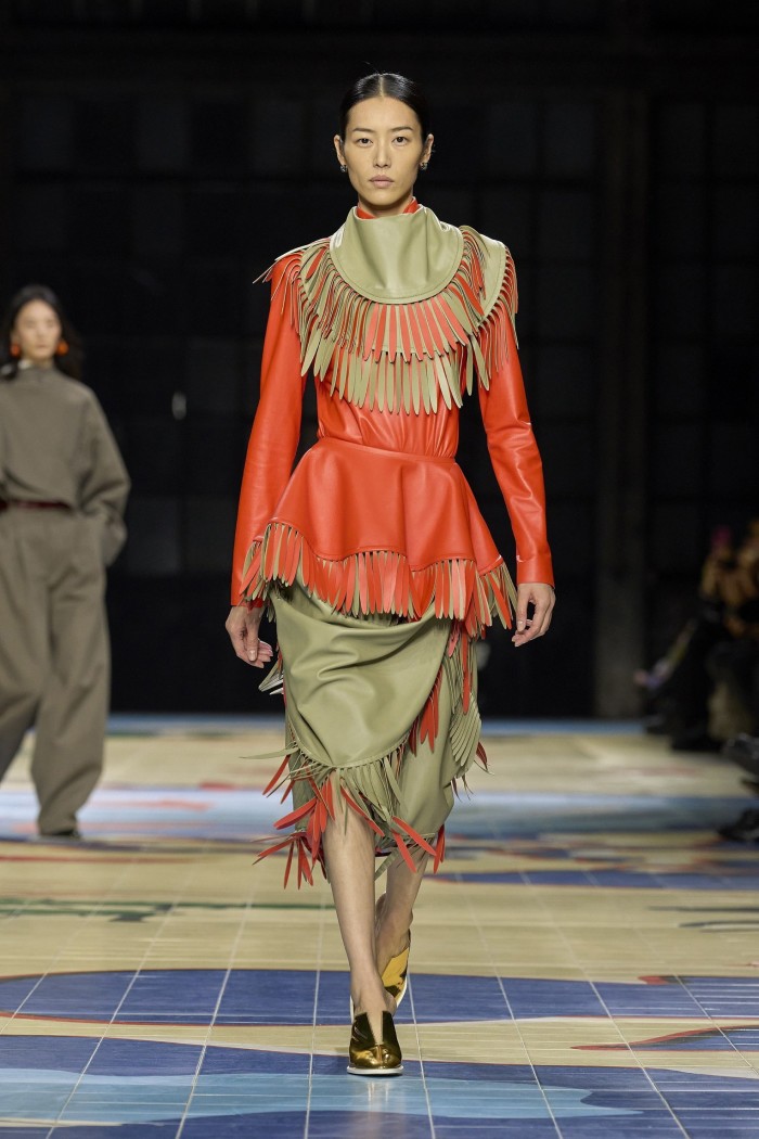 A catwalk model wearing a fringed leather dress 