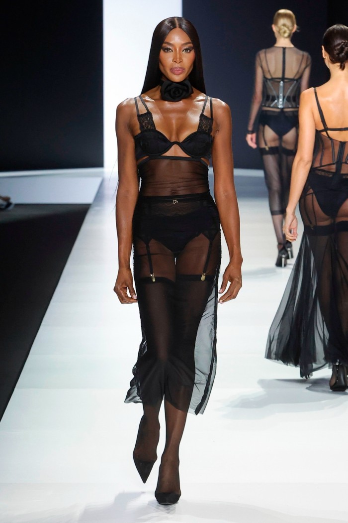 Naomi Campbell on the catwalk in a black silk bra and suspenders