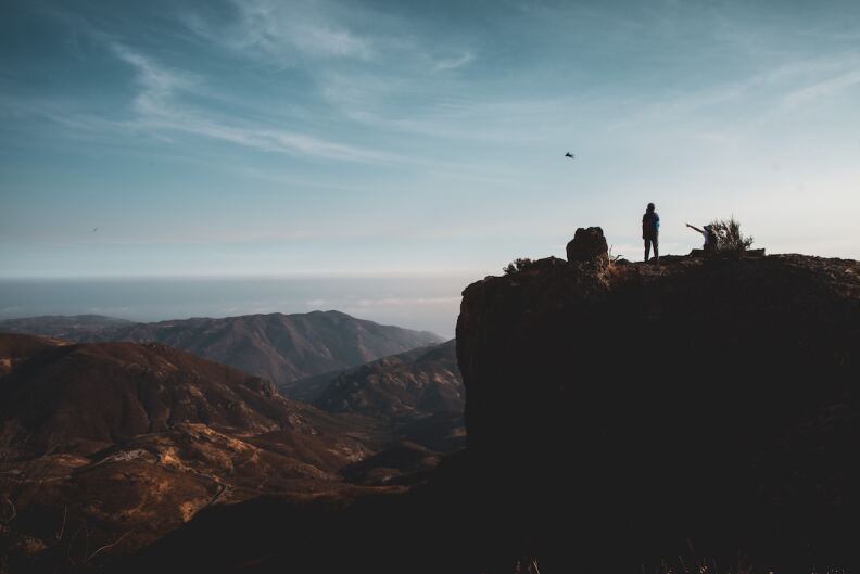 A man stands atop Sandstone Peak in Malibu.