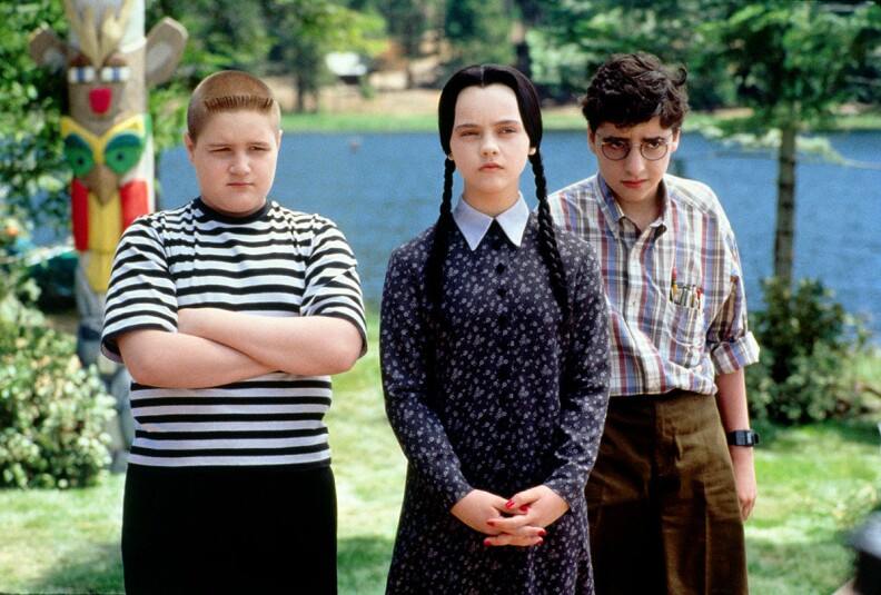 A still image from The Addams Family Values with Jimmy Workman in a striped shirt, Christina Ricci as Wednesday Addams and David Krumholtz as her nerdy love interest.