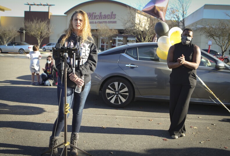 Sadie Martinez speaks at a microphone during a press conference held outside the Michaels store to confirm her and her husband, Eddie's innocence in a suspicious activity case brought on by Instagram influencer, Katie Sorensen. Sorensen accused the Martinezes of an attempted kidnapping of Sorensen's children in the Michaels parking lot.  Police found no evidence of a crime and the Martinezes believe it to be a case of racial profiling. Kinyatta Reynolds (right), a longtime friend of the Martinezes, stood by in support.