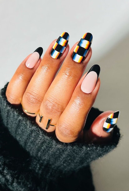 A trendy black & white nail art design for 2023 that combines checkered nails and black French tips.