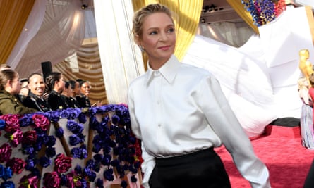 Uma Thurman at the Oscars, March 2022, wearing a buttoned-up white shirt with large cuffs and long black skirt