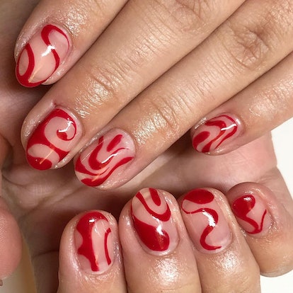 An abstract red swirl nail art design that nods to Taylor Swift's signature red lipstick.