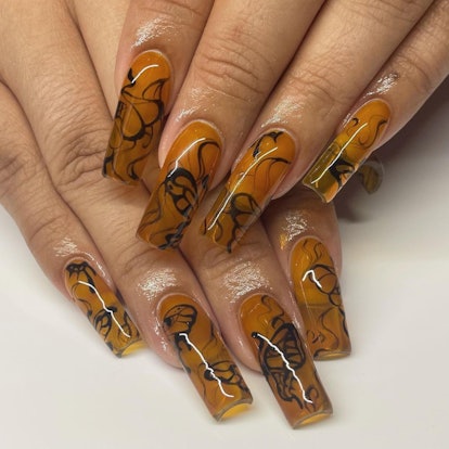 Abstract orange & black swirls are a cute pumpkin-inspired nail art design idea for fall 2023.