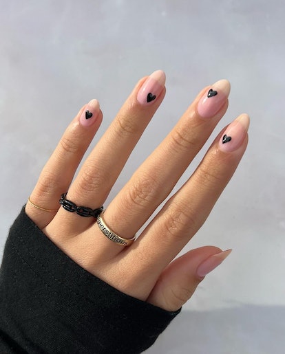 A minimal manicure design with tiny black heart nail art inspired by 