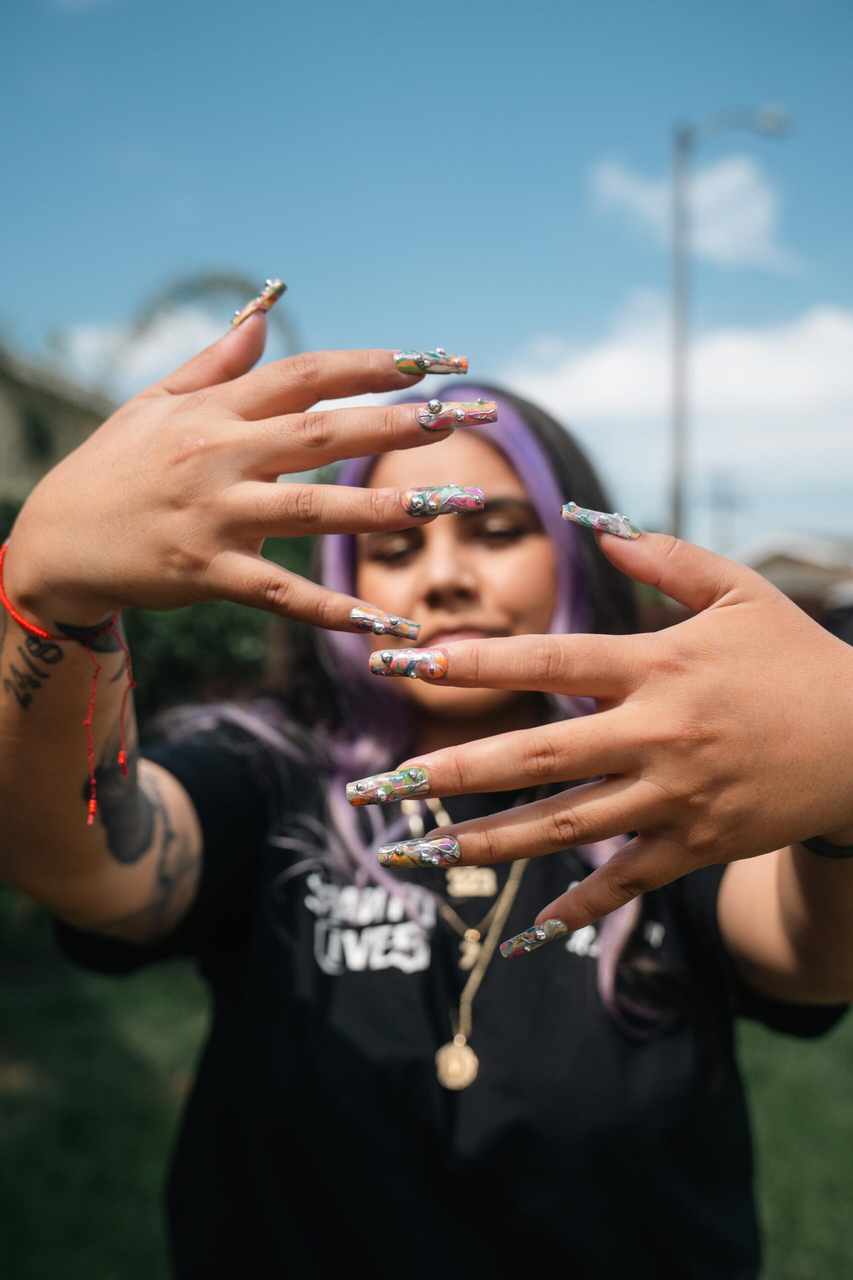 A woman holds her hands in front of her face, showing her fingernails