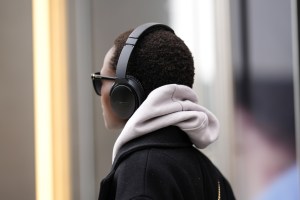 NEW YORK, NEW YORK - FEBRUARY 12: A guest wears black headphones from Bose, black sunglasses , a white hoodie sweater, a black long coat, outside Ulla Johnson, during New York Fashion Week, on February 12, 2023 in New York City. (Photo by Edward Berthelot/Getty Images)