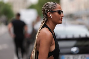 PARIS, FRANCE - JUNE 21: A fashion show guest is seen wearing black and green balenciaga shoes, long braids, black bottega veneta shades, a black top, black prada shorts an a black and gold chloe bag outside during the Bluemarble Menswear Spring/Summer 2024 as part of  Paris Fashion Week on June 21, 2023 in Paris, France. (Photo by Jeremy Moeller/Getty Images)