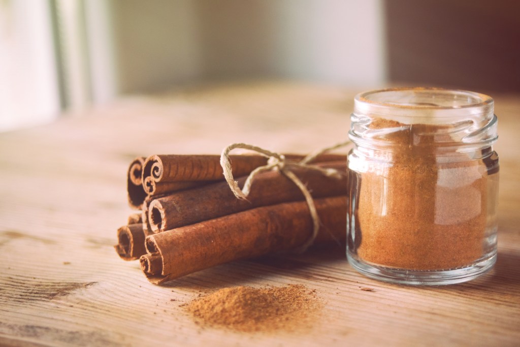 Cinnamon sticks next to cinnamon powder on table to use for thin lips