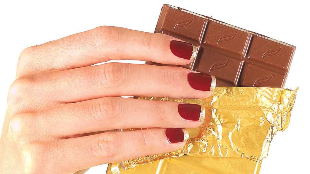 Red and gold French tip nails holding chocolate bar.